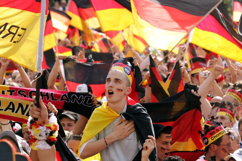 FILE - A German soccer fan sings the German national anthem prior to the beginning of the Round of 16 of the World Cup soccer match Germany against Sweden at the public viewing area where fans could watch the match live from Munich, on a giant television screen in Berlin, Saturday, June 24, 2006. Germany gets the 2024 European Championship underway against Scotland in Munich on Friday. However, away from the stadiums and public-viewing areas, few German flags are flying. Germany's dark history, rising far-right cast shadow on national pride before it hosts Euro 2024. (AP Photo/Franka Bruns, File)