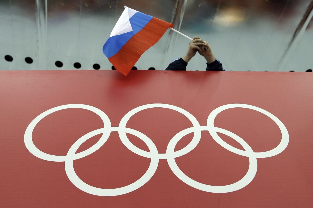 ARCHIVO - Una bandera rusa es desplegada encima de los anillos olímpicos