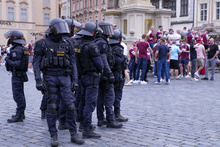 Riot police stands next to West Ham supporters hours before the Europa Conference League final soccer match between Fiorentina and West Ham United, in downtown Prague, Czech Republic, Wednesday, June 7, 2023. (AP Photo/Darko Bandic)