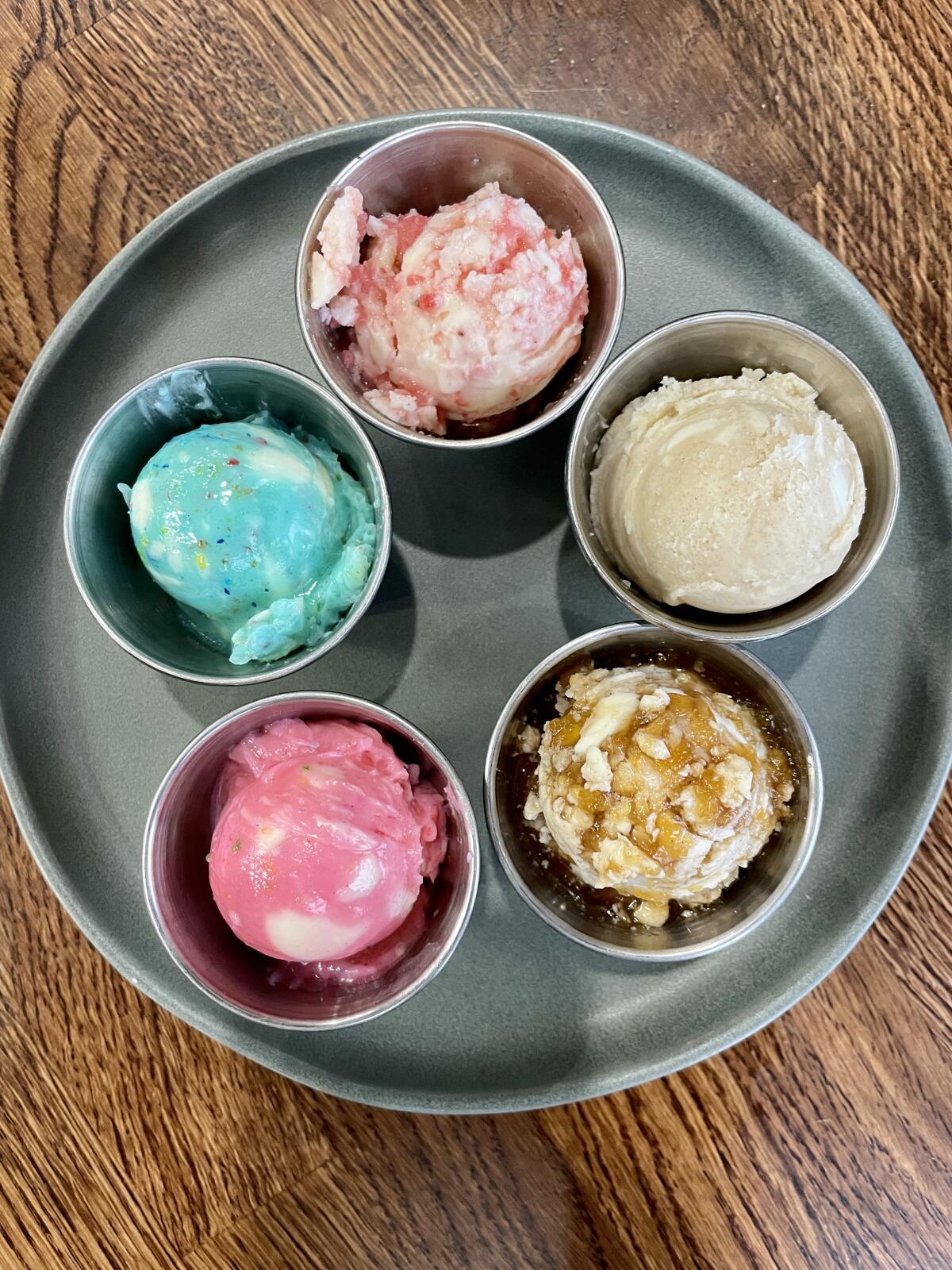 A round dish with five smaller cups of variously colored butters