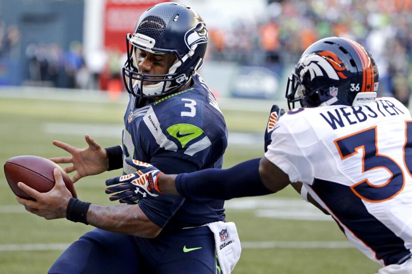 Seahawks quarterback Russell Wilson scrambles for yardage against Broncos cornerback Kayvon Webster during the winning drive in overtime Sunday.