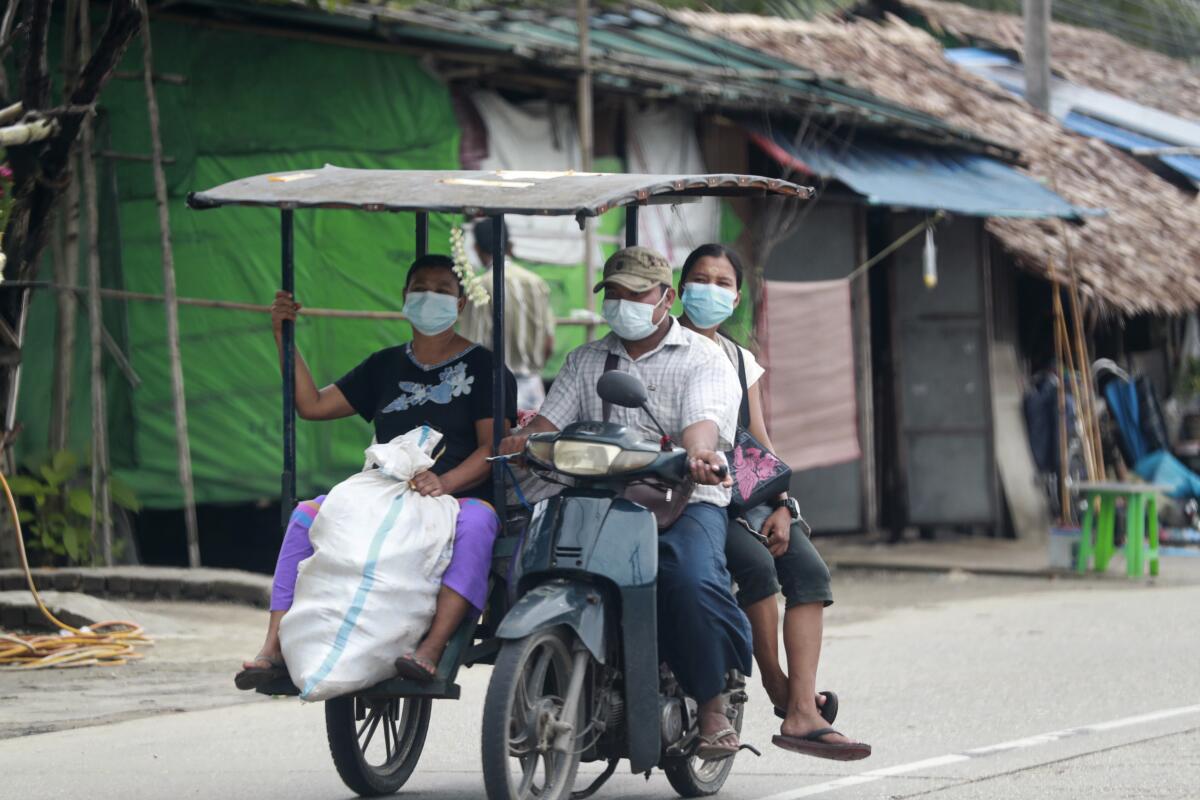 FILE - In this July 28, 2021, file photo, people wearing face masks to help curb the spread of the coronavirus ride a tricycle to transport goods in Shwe Pyi Thar township in Yangon, Myanmar. With coronavirus deaths rising in Myanmar, there are growing allegations from residents and human rights activists that the military government, which seized control in February, is using the pandemic to consolidate power and crush opposition. (AP Photo, File)