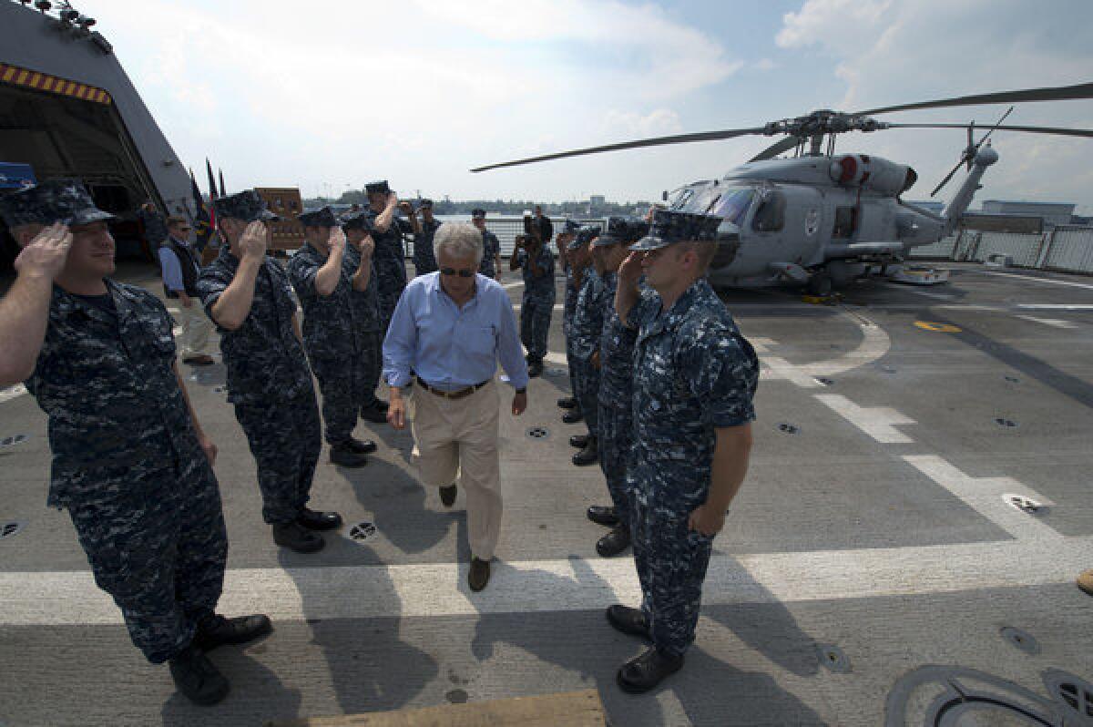 Defense Secretary Chuck Hagel, center, departs the Navy combat ship Freedom in Singapore.