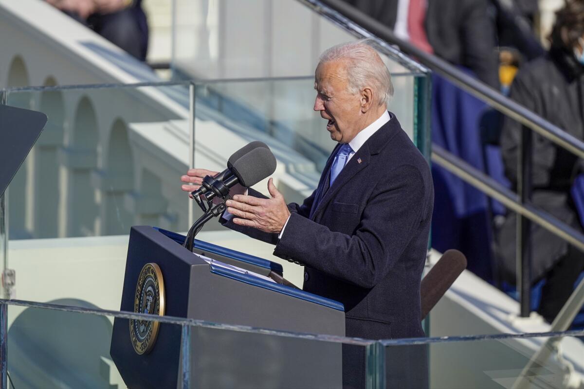 President Biden gestures while speaking at a lectern for his inaugural address outside the Capitol