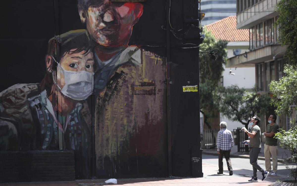 Un mural muestra a una joven portando una mascarilla, en Bogotá, Colombia.