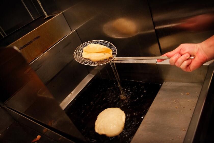 A puffy taco shell emerges from a deep fryer.