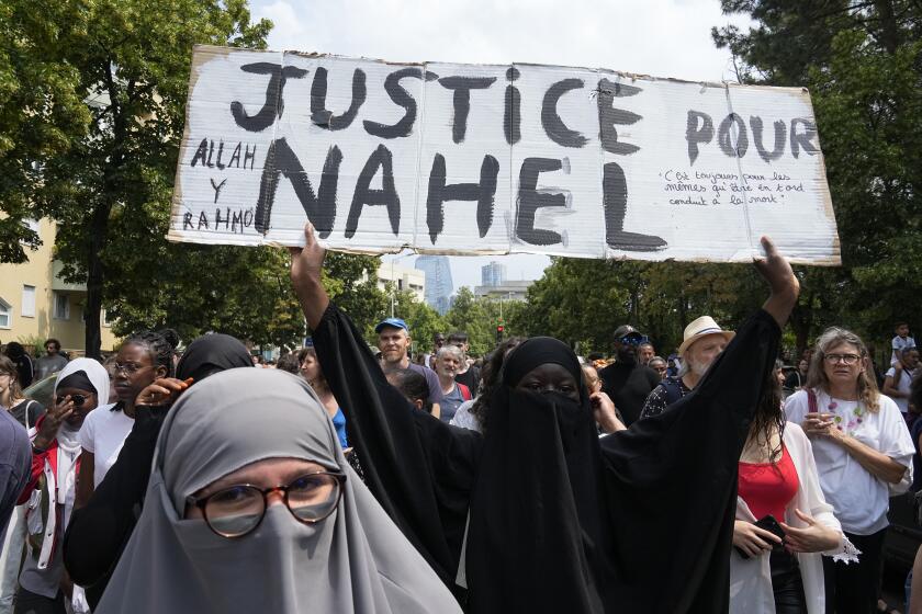 HOLD FOR STORY FRANCE POLICE SHOOTING FAR RIGHT BY ELAINE GANLEY - FILE - A woman shows a poster "Justice for Nahel" during a march for 17-year-old Nahel, Thursday, June 29, 2023 in Nanterre, outside Paris. Riots that spread from small-town France to cities, sparked by the killing by a police officer of a teenager with North African roots, revealed the depth of discontent roiling poor neighborhoods _ and gave the far right a new platform amid growing signs that its anti-immigration mantra is seeping across a once-iron-clad political divide. (AP Photo/Michel Euler, File)