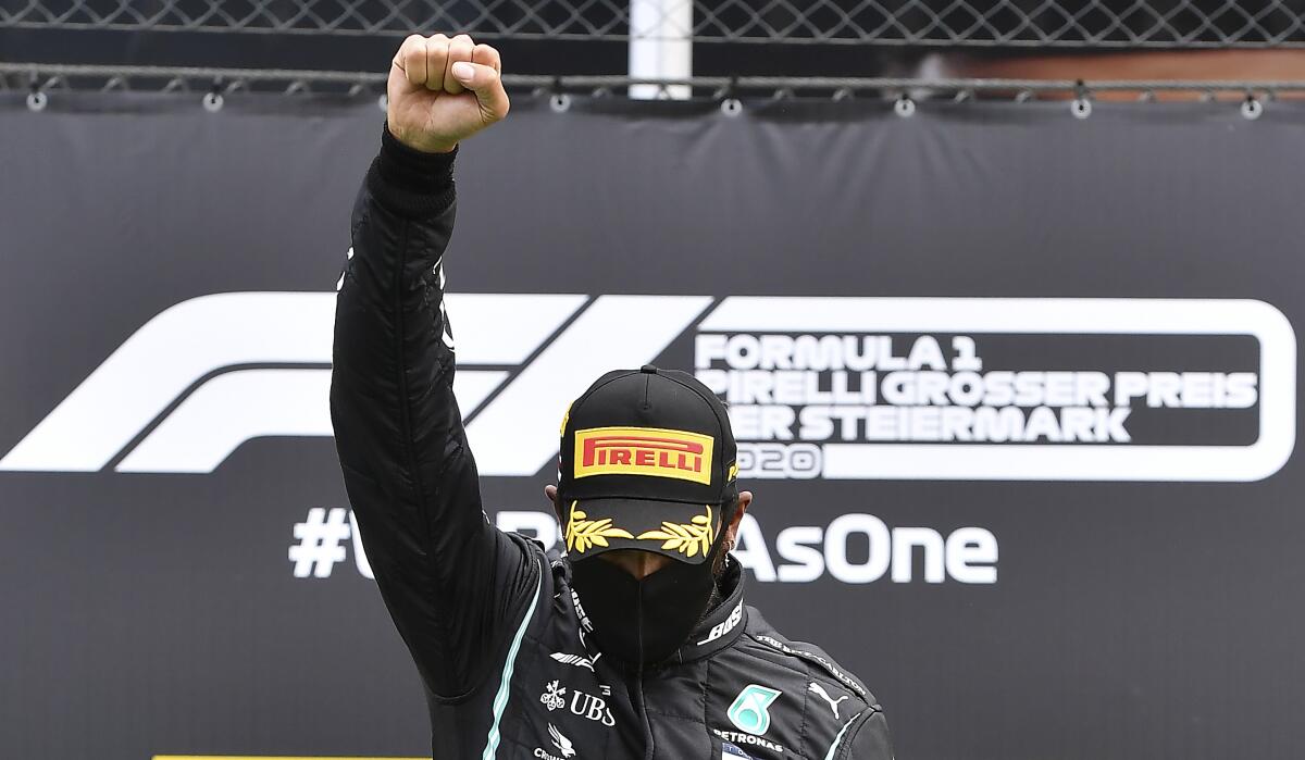Lewis Hamilton raises his right fist on the podium after winning a race in Spielberg, Austria.