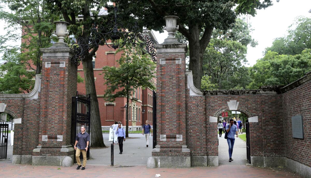 Pedestrians walk through the gates of Harvard Yard at Harvard University.