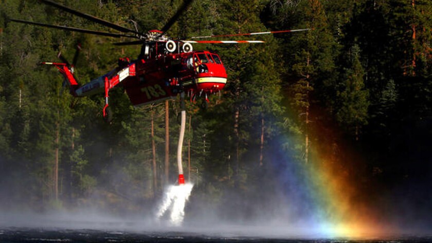 A fire helicopter scoops up water from Jenks Lake as it works to control flames in the Big Bear area.