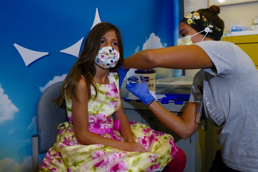 San Diego, CA - November 03: On Wednesday, Nov. 3, 2021 in San Diego, CA., at Rady Children’s Hospital, Violet Walsh, 8 from Bay Park wore a dress for what she called “vaccinate day”, and was not the least bit afraid of receiving the Pfizer vaccine specifically for children age 5-11 years old from Jillian Mercer, RN. (Nelvin C. Cepeda / The San Diego Union-Tribune)