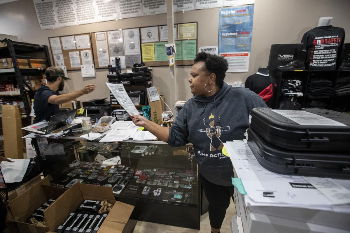 Geneva Solomon, right, works through a crush of paperwork for gun purchasers at Redstone Firearms in Burbank. 