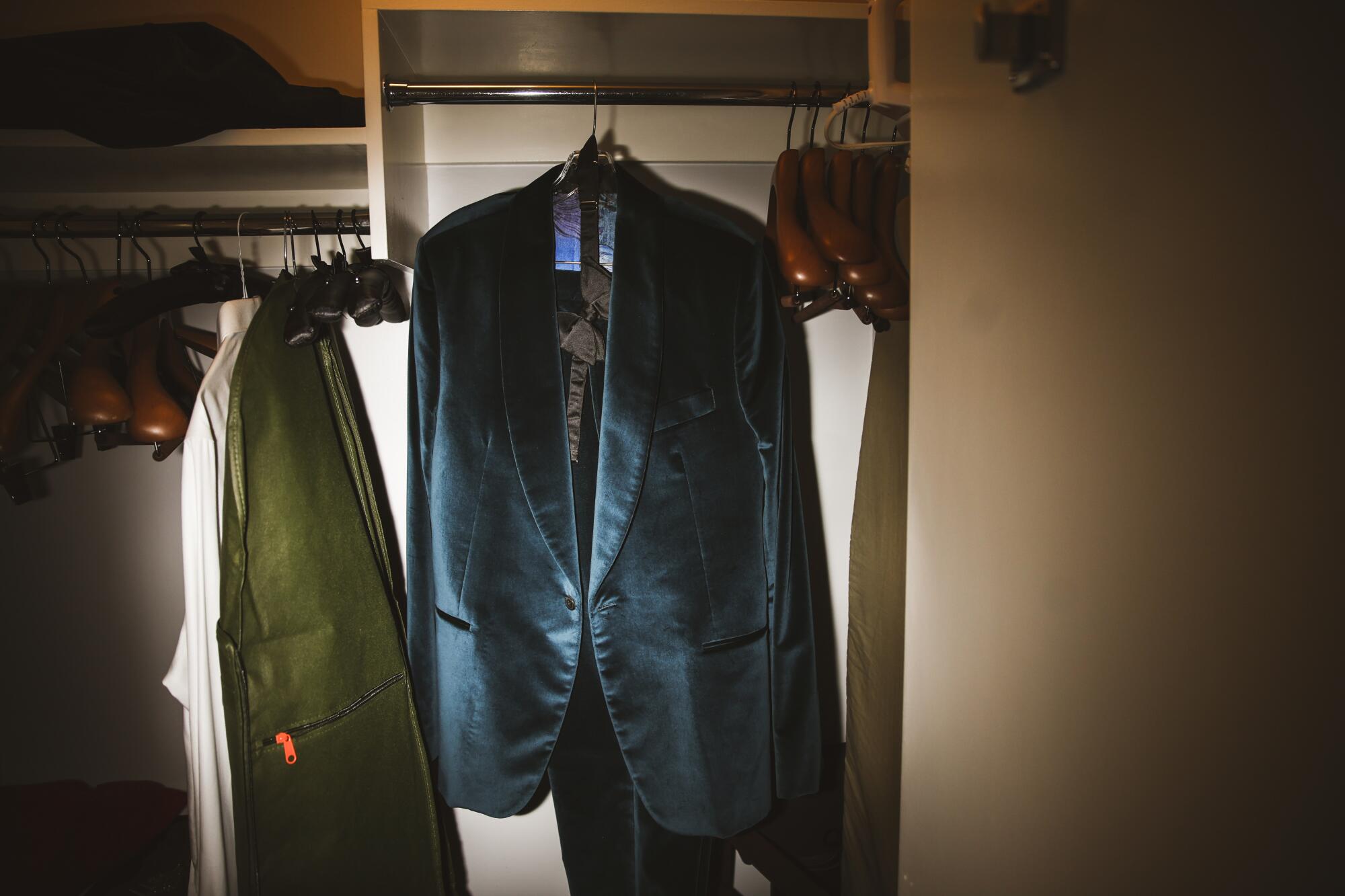 A tuxedo hangs in a closet.
