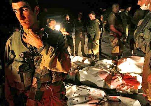 Israeli soldiers stand near bodies, which they claim are dead Hezbollah fighters, after transporting them from Lebanon to the northern Israeli town of Yiron Wednesday.