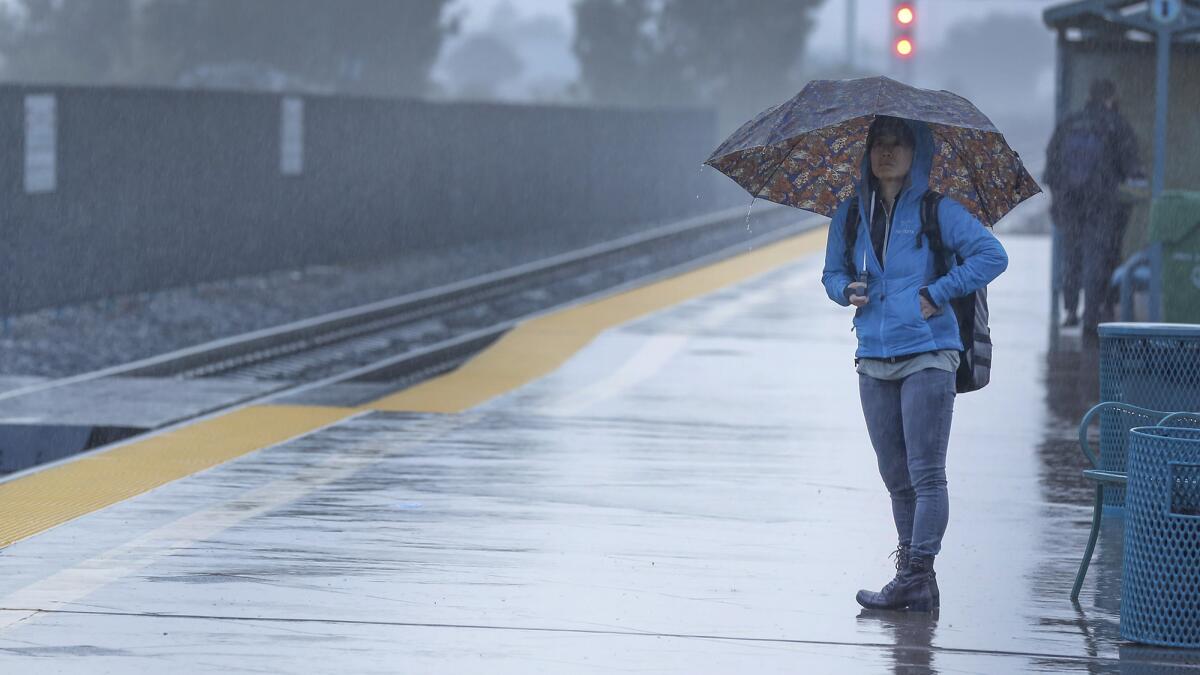 A morning commuter waits in the rain at the Irvine Transportation Center.