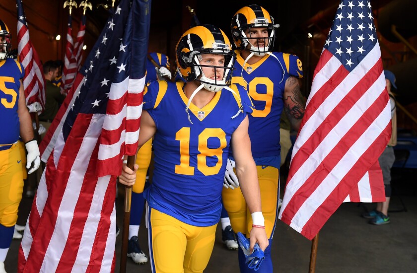 Los Angeles Rams players wait to take the field with American flags.