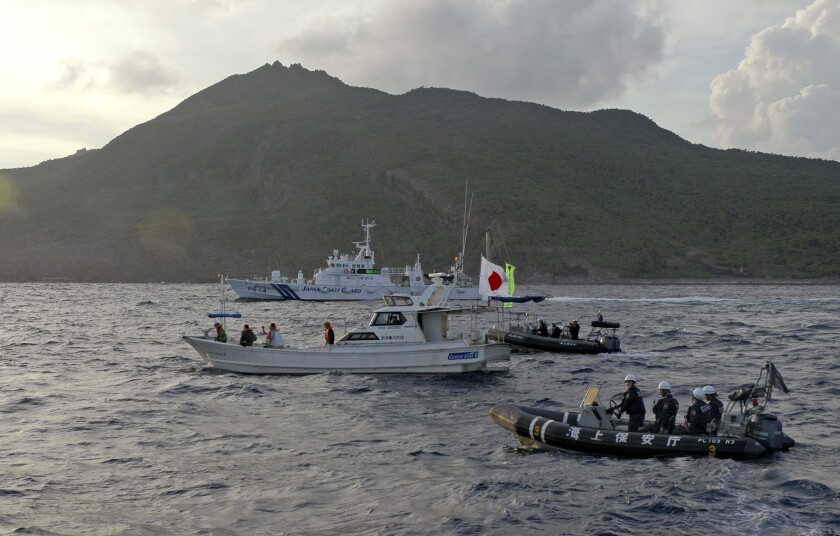 FILE - Japanese Coast Guard vessel and boats, rear and right, sail alongside a Japanese activists' fishing boat, center with a flag, near a group of disputed islands called Diaoyu by China and Senkaku by Japan, early Sunday, Aug. 18, 2013. Japan protested to Beijing after spotting Chinese and Russian warships just outside of Japanese territorial waters around the disputed East China Sea islands earlier Monday, July 4, 2022, prompting criticisms from China. (AP Photo/Emily Wang, File)