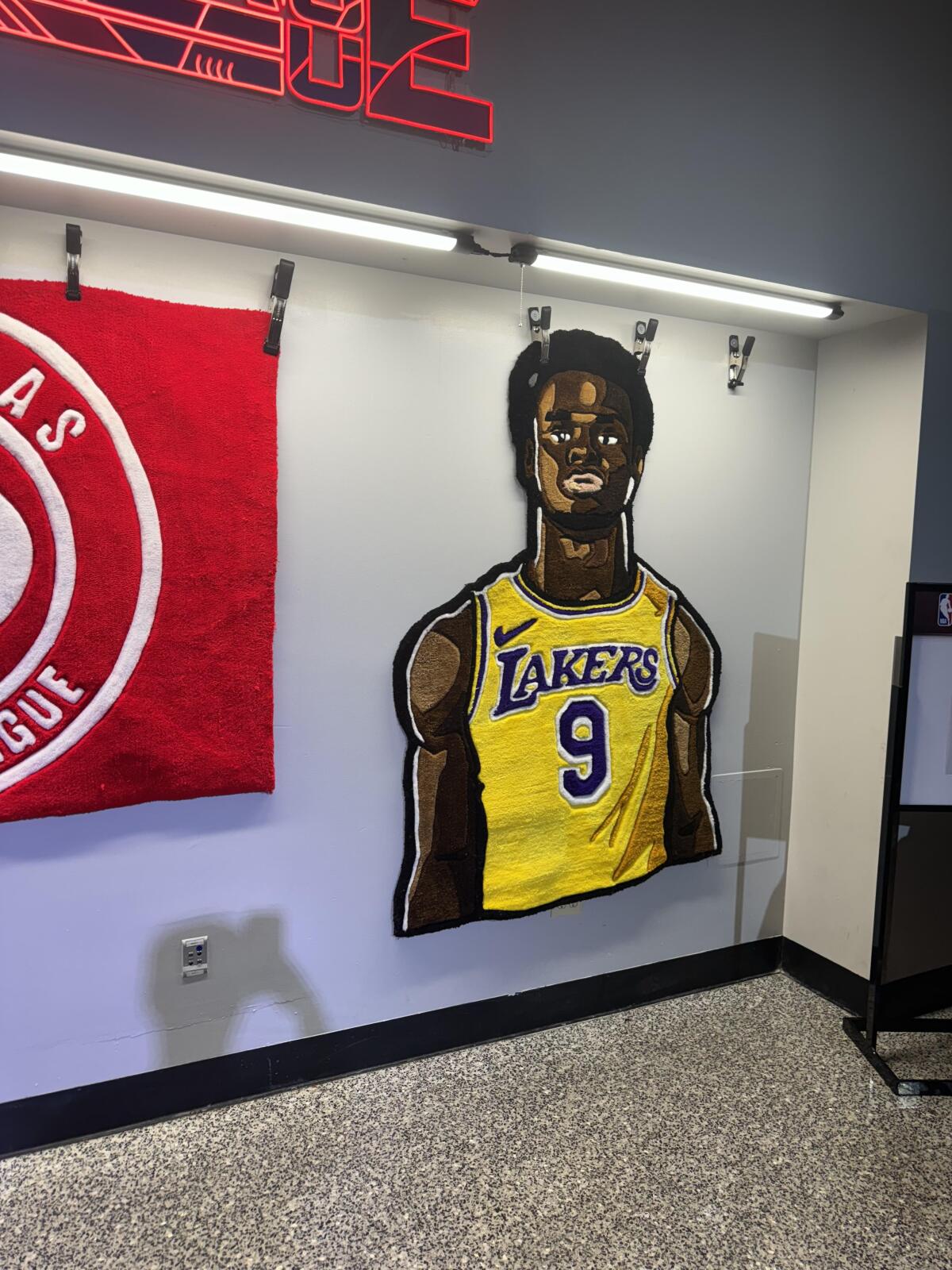 A custom throw rug depicting Bronny James hangs under a spotlight in the concourse at the NBA’s Summer League.