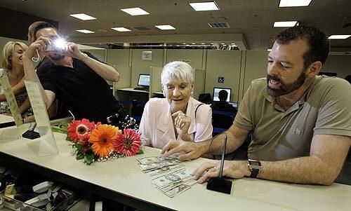 Paul Waters, right, counts out the money for a marriage license at the Ventura County clerk and recorder's office. The cash was a gift from his mother, Peggy Waters, seated at his side. Kevin Voecks, his partner and soon to be his spouse, takes a photo. They have lived together for 15 years and were among the first couples to get married Tuesday in Ventura County.