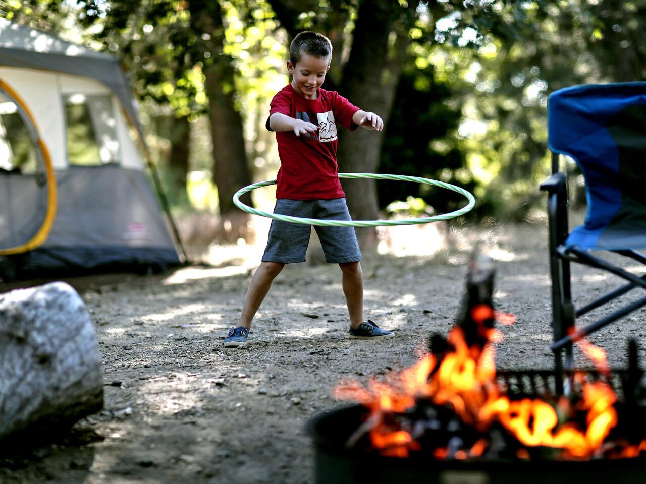 Caleb Divine, 8, hula hoops by his family’s campfire at Mountain Oak.