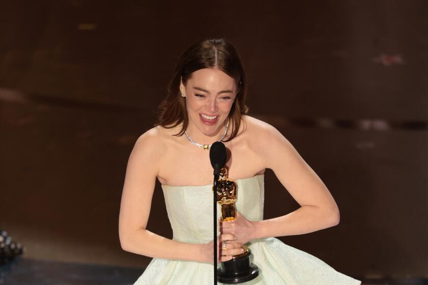 Emma Stone speaks into a microphone holding an oscar