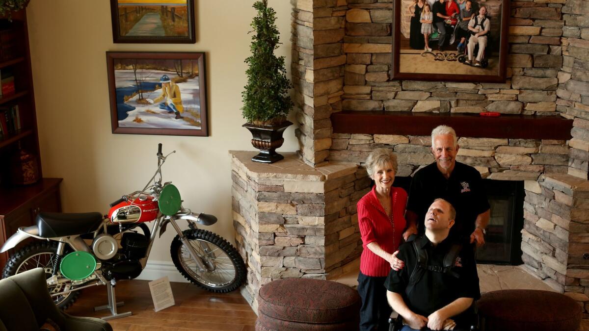 White stands with wife Dani and son Bradley in the family living room, which like every room in the house also contains a vintage motorcycle — in this case a 1969 Husqvarna race bike.