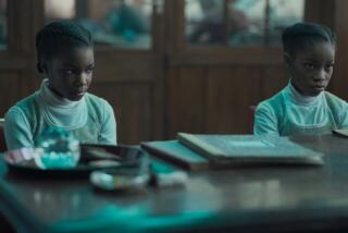 Two girls dressed identically sitting at a dejsk in the movie "The Silent Twins."