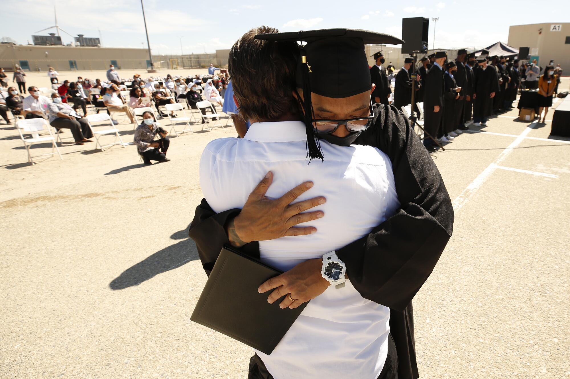 Clifton Lee Gibson, who has already graduated from the Cal State LA's Prison B.A. Program earlier hugs graduate Dara Yin