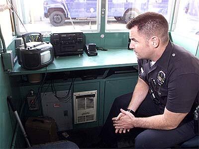 Los Angeles Police Officer Ken Hurley watches the decision on a small television.