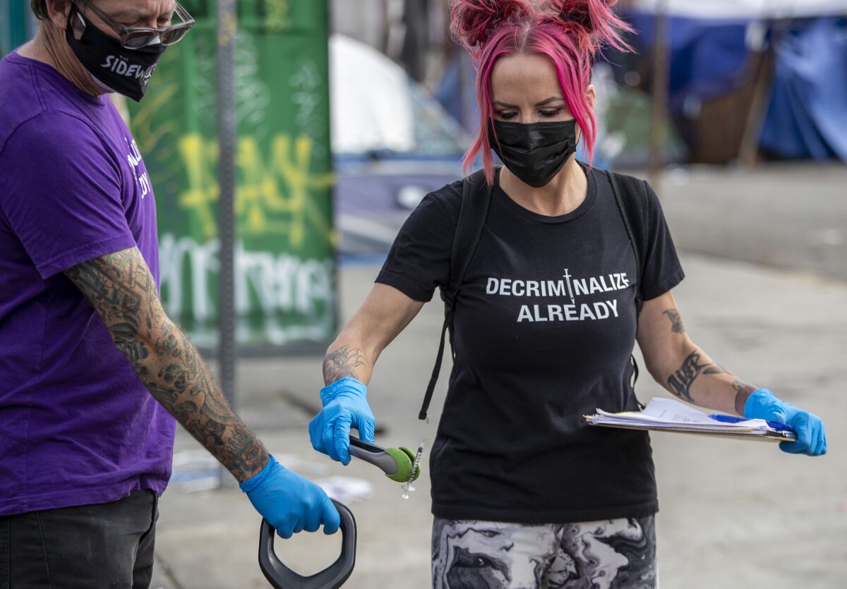 Sidewalk Project volunteers Joe Oneill and Jen Elizabeth collect discarded syringes on skid row.