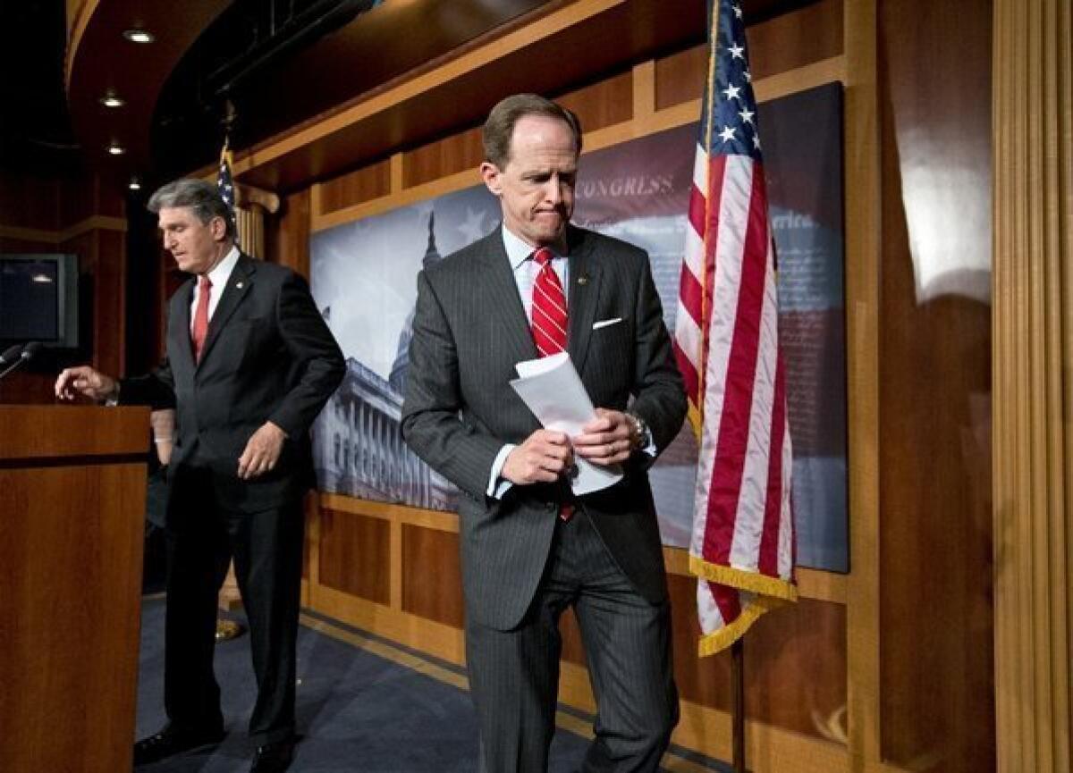 Sens. Pat Toomey (R-Pa.), right, and Joe Manchin (D-W.Va.) finish a news conference in Washington on Wednesday announcing that they have reached a compromise on background checks for gun buyers.