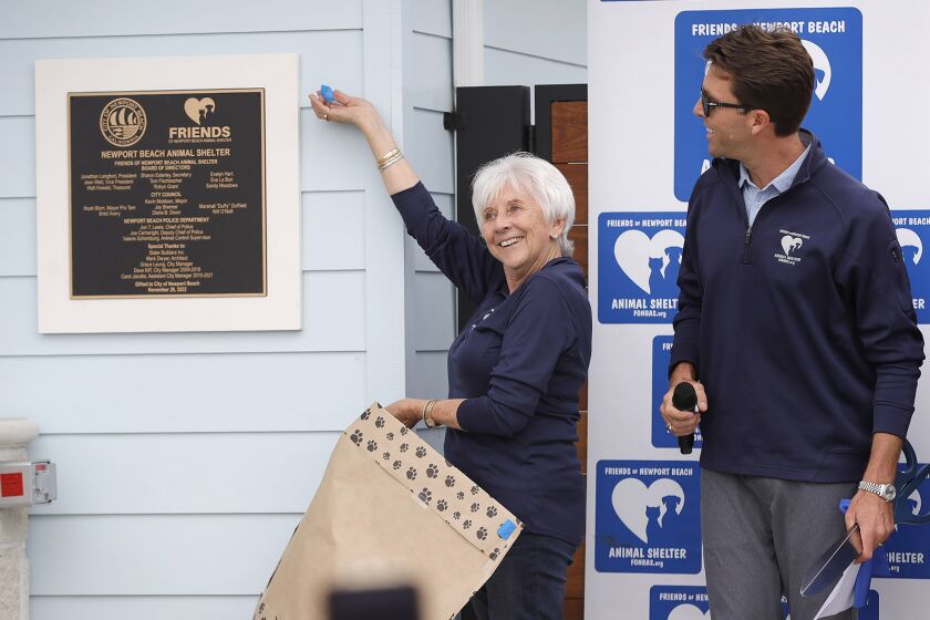 Secretary Sharon Esterley and President Jon Langford, from left, unveil new ceremonial wall plaque during ribbon cutting and grand opening ceremony for the new Newport Beach Animal Shelter on Thursday.