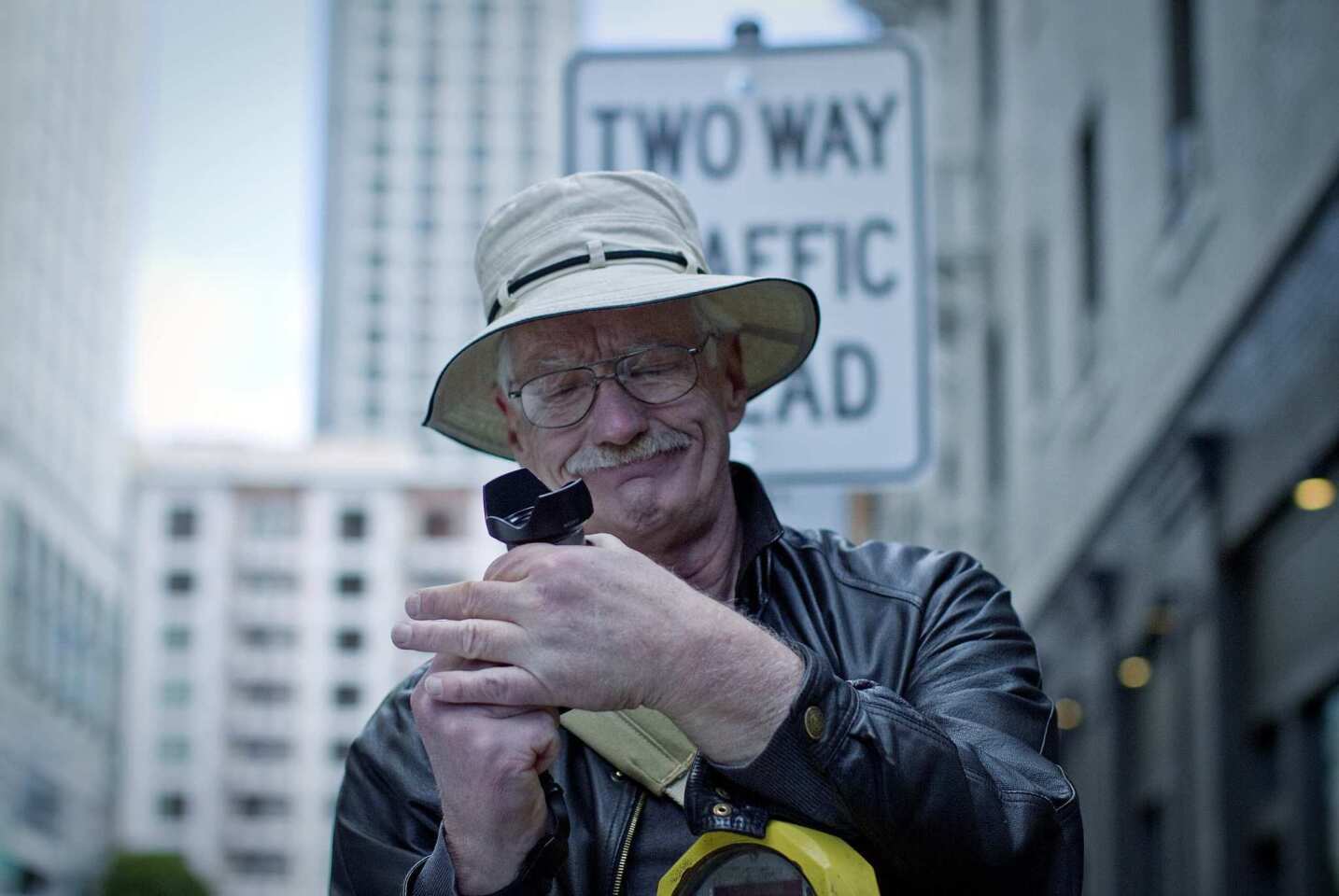 Leaning on a parking meter, Mark Ellinger adjusts his camera to photograph some of his favorite architecture in San Francisco's Tenderloin district.