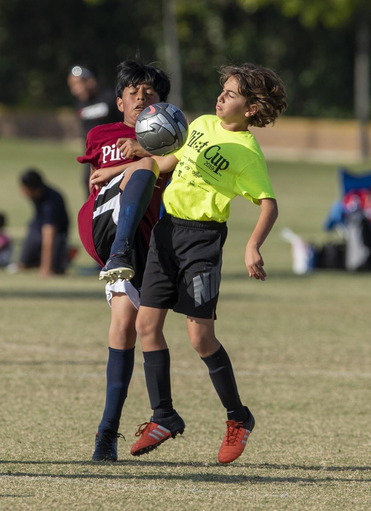 Pomona Elementary's Derick Leyva, left, and Newport Coast's Grant Davidson battle for a ball in a boys' fifth- and sixth-grade Silver Division pool-play match at the Daily Pilot Cup on Thursday.