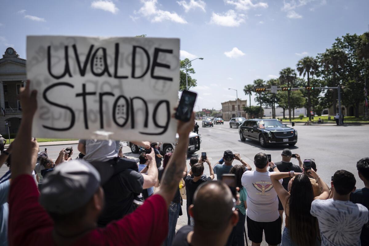 Onlookers, one with a sign reading "Uvalde Strong," watch President Biden's motorcade.