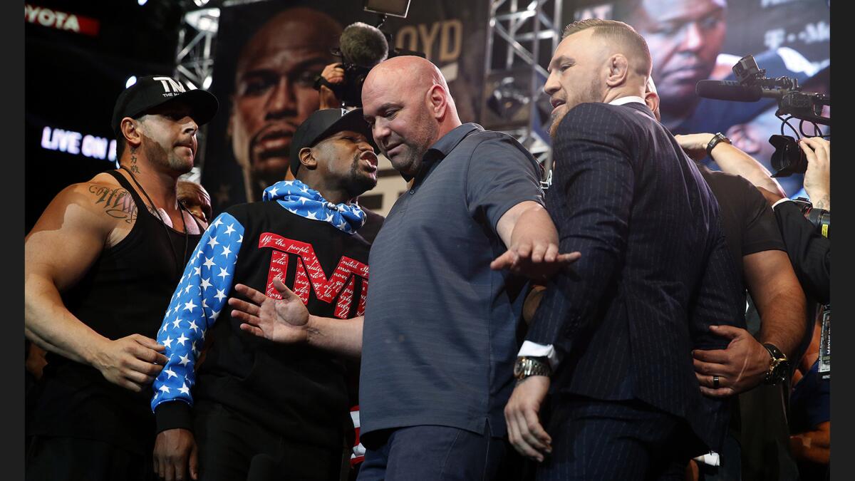 Floyd Mayweather Jr., left, and Conor McGregor have to be separated by UFC president Dana White after standing toe to toe after a press conference at Staples Center.