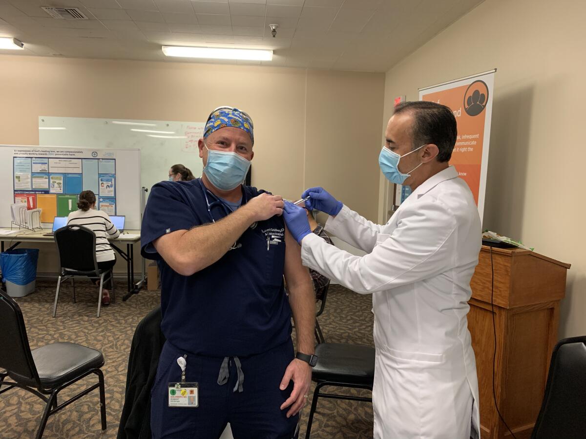 Dr. Robert Goldberg, left, receives his vaccine.