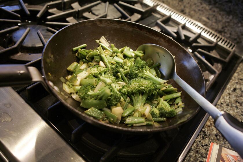 Broccoli and other vegetables cook in a pan for a stir fry.