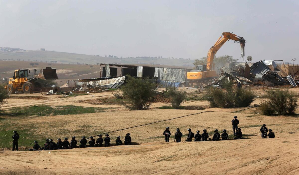 Israeli policemen stand guard as bulldozers demolish homes in the Bedouin village of Um al Hiran.