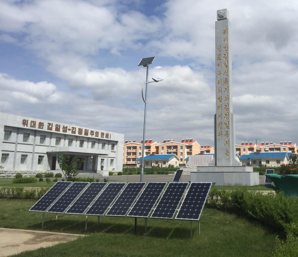 Solar panels, and a solar powered streetlight, at a farm complex on the outskirts of Pyongyang, North Korea. The worker housing in the distance has solar water heaters on the roof. (Julie Makinen / Los Angeles Times)