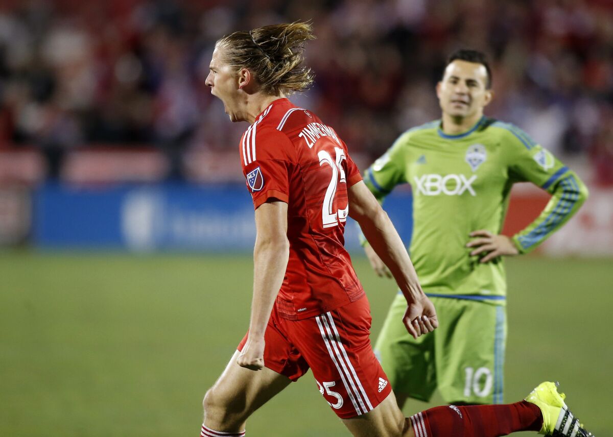 FC Dallas defender Walker Zimmerman (25) reacts to scoring the team's second goal as Seattle midfielder Marco Pappa (10) looks on during a 2015 game.