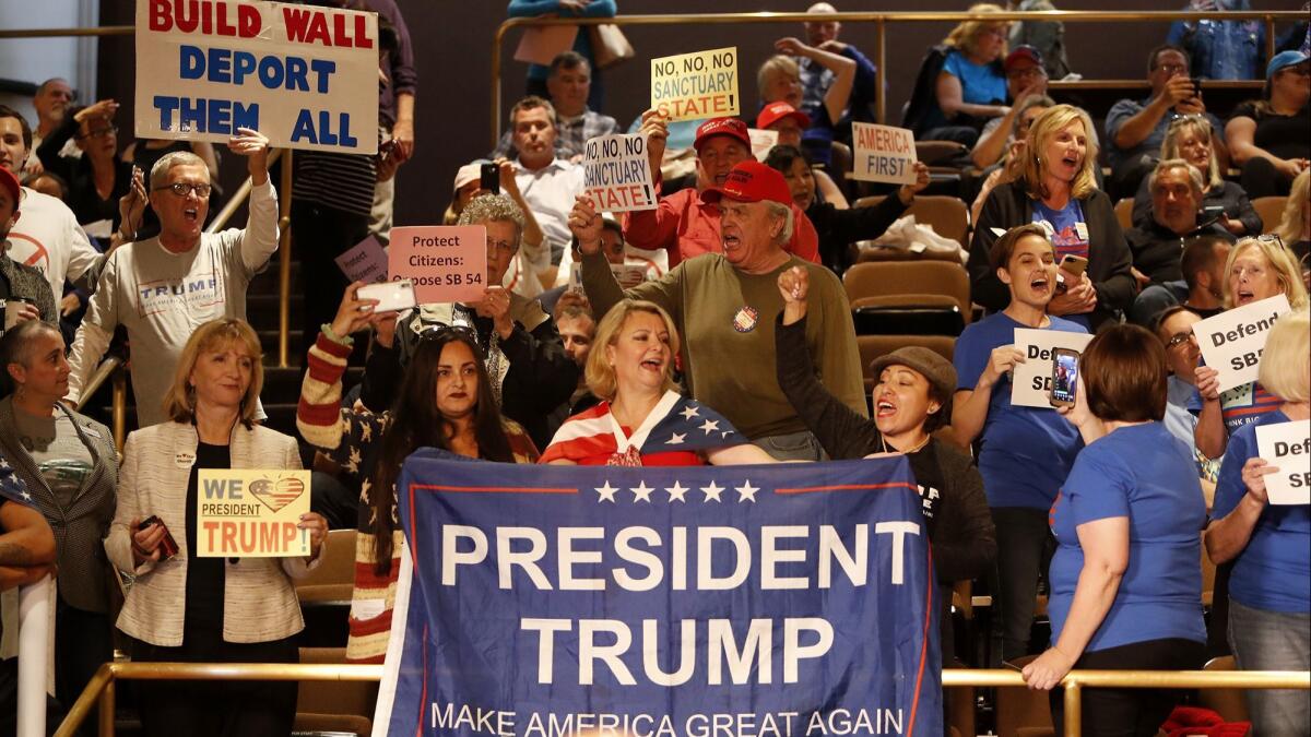 Opponents of Senate Bill 54, or the California Sanctuary State Bill, hold up signs during a Huntington Beach city Council meeting.
