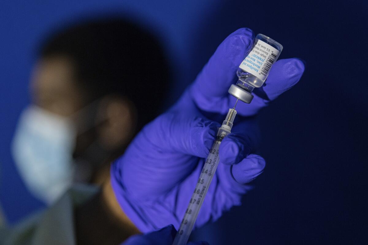 A gloved hand holds a syringe with a dose of mpox vaccine.