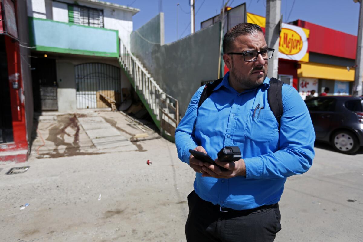 Isaí Lara Bermúdez, un reportero de investigación de Zeta, cubre un homicidio en el complejo residencial El Refugio, en Tijuana. Lara ha sido amenazado por sus artículos (Gary Coronado / Los Angeles Times)