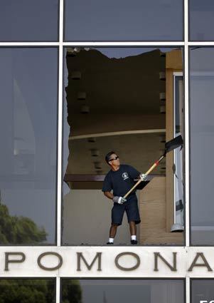 A worker cleans up shattered glass at Pomona City Hall.