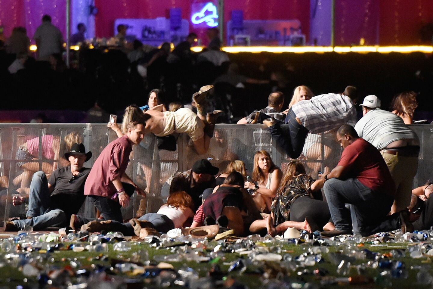People take cover at the Route 91 Harvest country music festival after hearing gunfire Sunday night in Las Vegas. The shooter was firing from the nearby Mandalay Bay Resort and Casino.