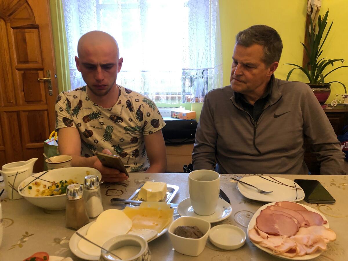A Ukranian refugee shares some of the images sent to him from friends still in the country with Bryan Haney, right.
