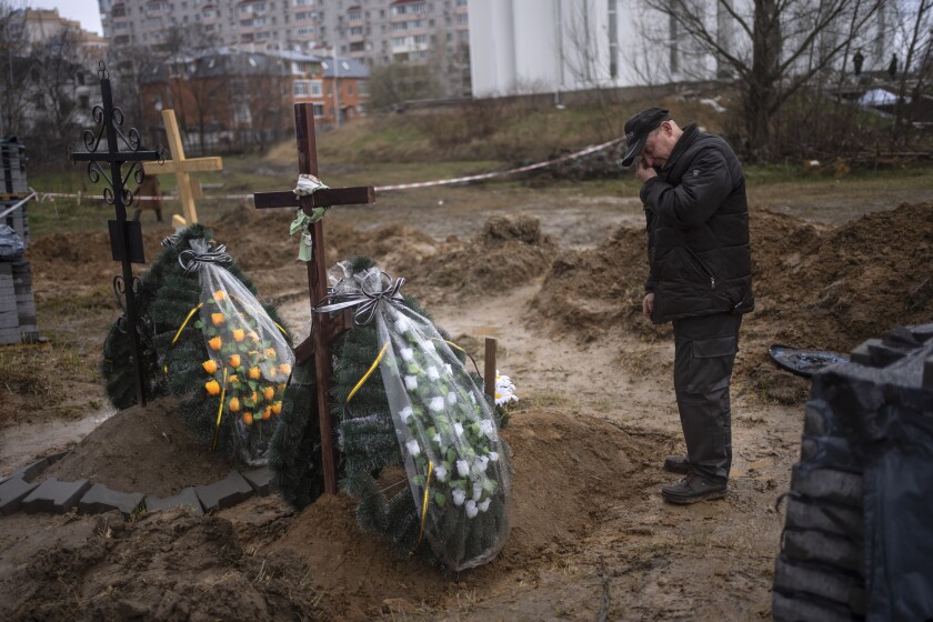 A man mourns in front of a fresh grave.