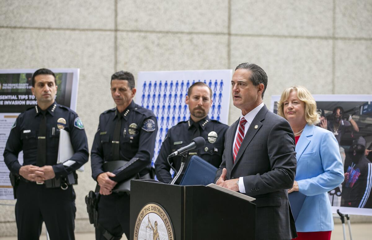 O.C. Dist. Atty. Todd Spitzer speaks during a news conference as three police officers and a politician stand behind him.