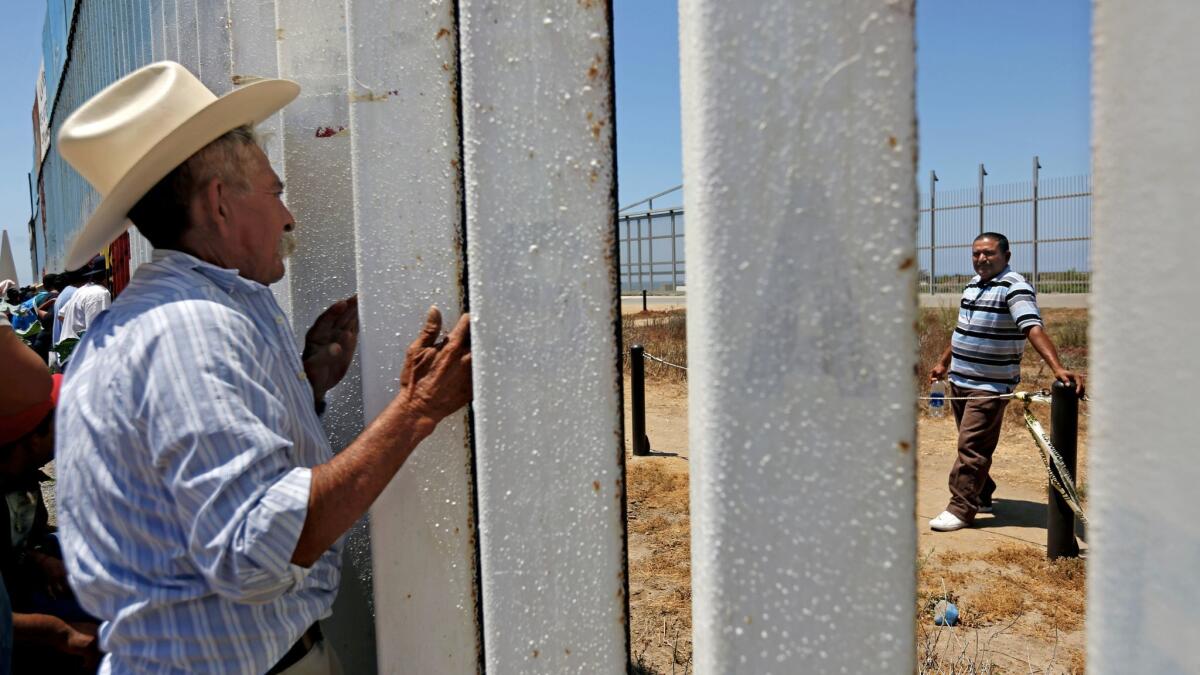 Mauro Mejia, 63, of Nayarit, Mexico, peers through the fence at the beach in Tijuana, to visit with his son Ricardo Mejia, 44, right, of Riverside, whom he had not seen in 25 years.